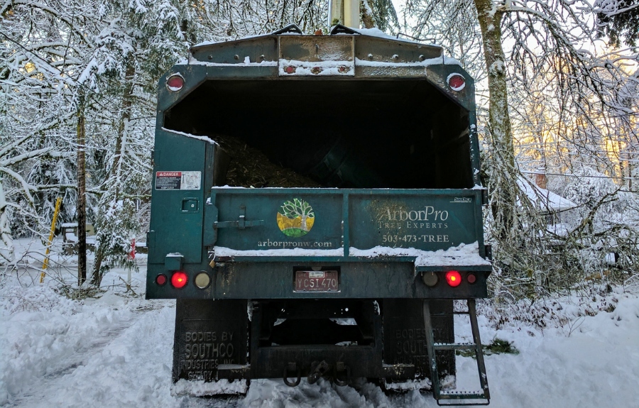 ArborPro Tree Experts professional chipper and bucket truck positioned in snowy winter conditions demonstrating ideal tree pruning timing in Portland area.