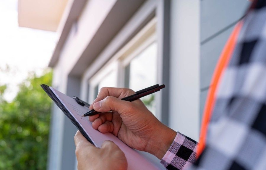 An ArborPro Certified Arborist holding a clipboard and taking written notes during a tree health inspection outside a Lake Oswego area home.
